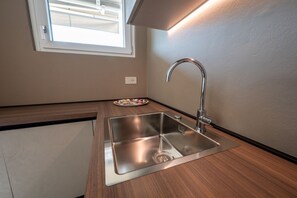 A kitchen with a stainless steel sink, a window above it, and a wall-mounted light. - Lake Iseo - Waterfront House | Sarnico (Sarnico)
