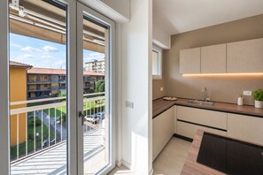 A modern kitchen with a built-in oven, a sink, and a window overlooking a residential area. - Lake Iseo - Waterfront House | Sarnico (Sarnico)