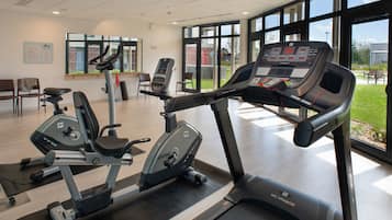 Een sportschool met cardioapparatuur, een loopband en een roeimachine.
