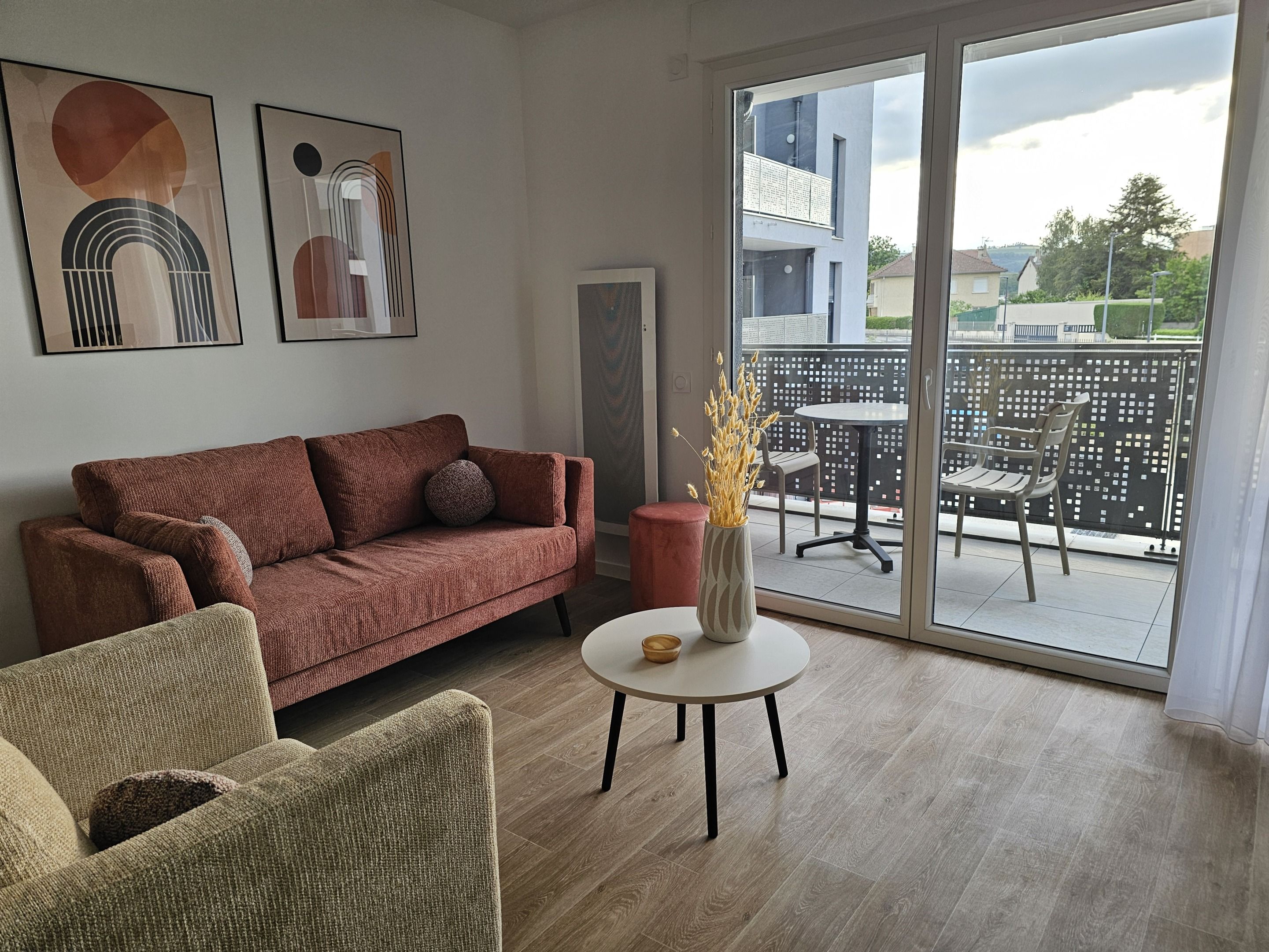 Un salon moderne avec un canapé, une table ronde et une vue sur le balcon.