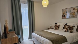 A bedroom with a bed, a bedside table, a lamp, a painting, and a view through the window. - DOMITYS - Les Passementiers (Villars)