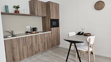 A modern kitchen with wooden cabinets, a built-in microwave, a sink, and a dining area with a table and chairs.
