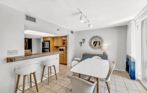 A modern kitchen with a central island, bar stools, and a dining table with chairs.
