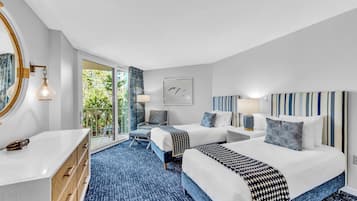 A hotel room with two beds, a large window, a balcony, and a view of greenery.