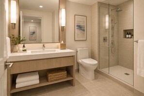Un baño moderno con ducha envuelta en vidrio, un lavabo blanco y un inodoro.