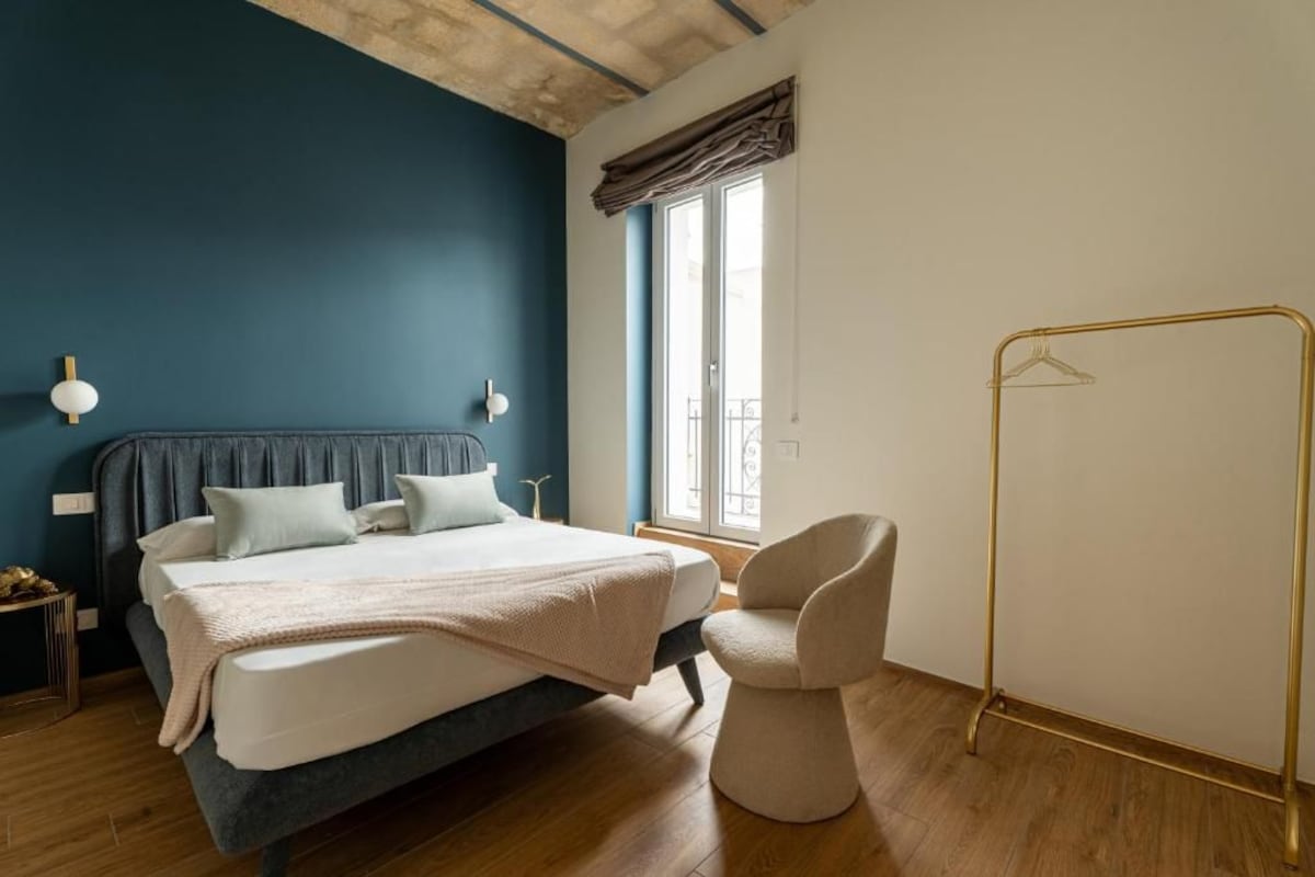 A bedroom with a bed, bedside table, and a chair.