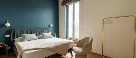 A bedroom with a bed, bedside table, and a chair.