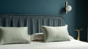 Ein Bett mit dunklem Kopfteil, zwei Kissen und einer Wandleuchte.