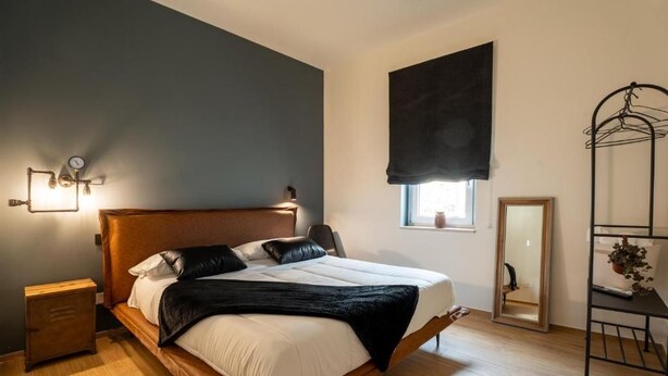 Ein Schlafzimmer mit einem Holzbett, Nachttischlampen, einem Fenster mit Ausblick und einem Spiegel.