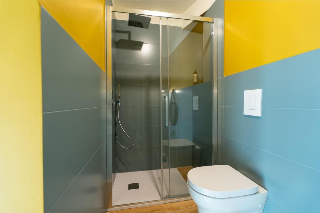 A bathroom with a glass-enclosed shower, a toilet, and a sink.