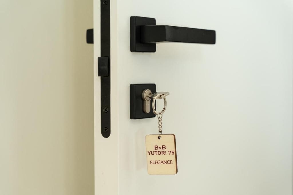 Una puerta con manija negra y un llavero con placa de identificación.