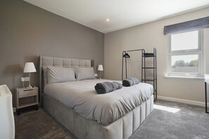 A bedroom with a bed, bedside tables, a window, and a view. - The Olive Tree | Deluxe 1-Bed Apartment (Kingston upon Hull)