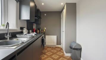 A modern kitchen with a black countertop, stainless steel sink, and a built-in oven.