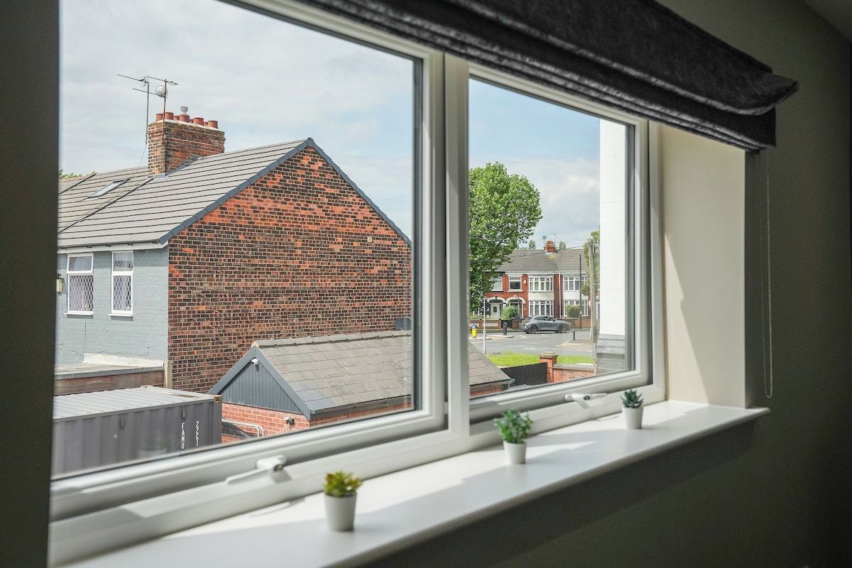 A window with a view of a brick house and a street.