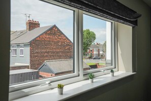 A window with a view of a brick house and a street. - The Olive Tree | Deluxe 1-Bed Apartment (Kingston upon Hull)