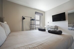 A hotel room with a bed, a desk, a TV, and a window. - The Olive Tree | Deluxe 1-Bed Apartment (Kingston upon Hull)
