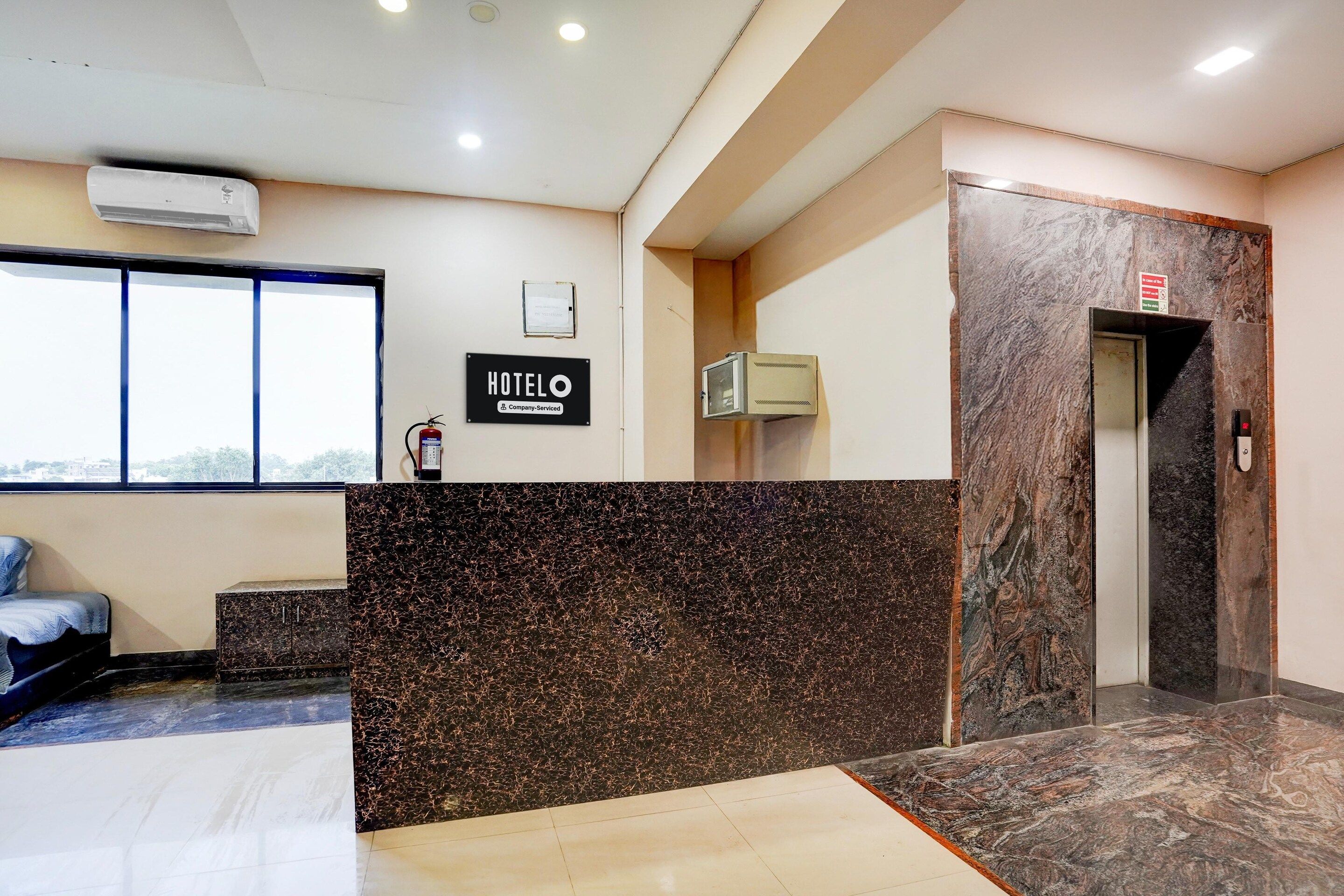 A hotel reception area with a marble counter, a sign reading 'HOTELO,' an elevator, and a window with a view.