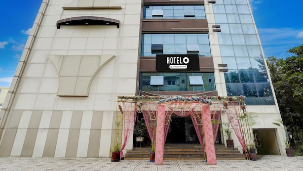 A modern hotel building with a prominent 'HOTEL' sign, a glass facade, and a decorative entrance with potted plants. - Hotel O Rani Durgawati Crossway (Nagpur)