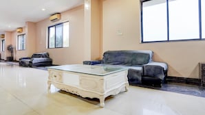 A spacious room with a glass-top coffee table, a sofa, and a large window providing natural light. - Hotel O Rani Durgawati Crossway (Nagpur)
