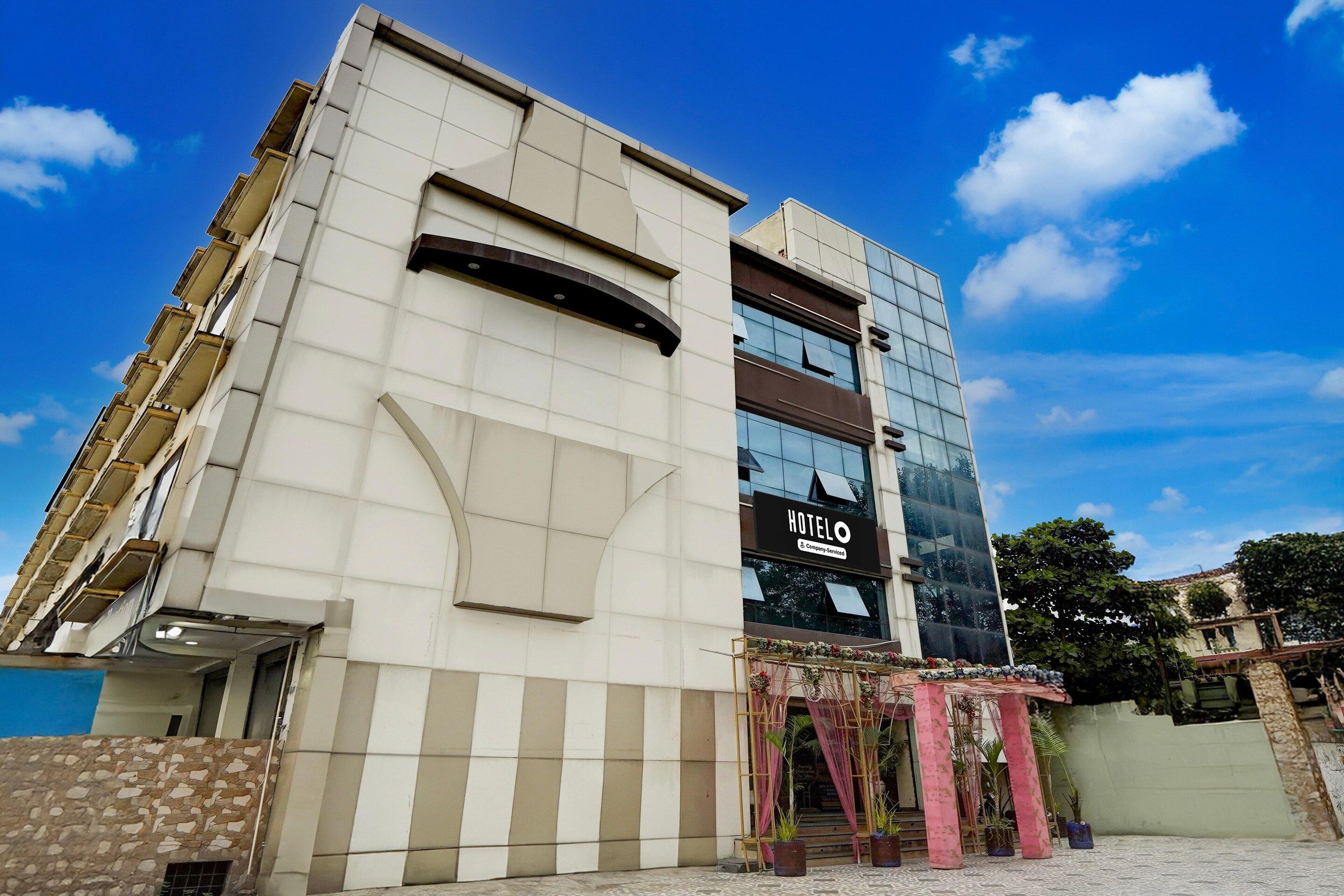 A hotel with a modern facade, a prominent entrance with a decorative arch, and a clear blue sky.