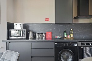 A compact kitchen with a microwave, toaster, kettle, and a dish rack. - The Olive Tree | Superior 2-Bed Apartment (Kingston upon Hull)