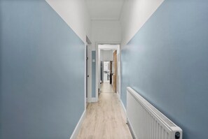 Un pasillo estrecho con paredes azul claro y suelo de madera.
