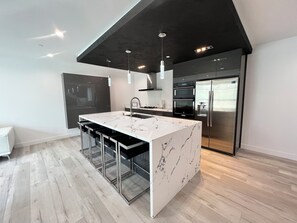 Eine moderne Küche mit einer großen Kochinsel, Edelstahlgeräten und minimalistischem Design.