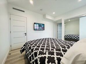 Ein Schlafzimmer mit einem Bett, einem Fernseher an der Wand und einer Tür.