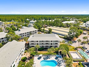 Ein mehrstöckiges Hotel mit Schwimmbad, umgeben von Grünflächen und weiteren Gebäuden.