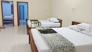 Quarto de hotel com três camas, piso ladrilhado e porta para outro cômodo.
