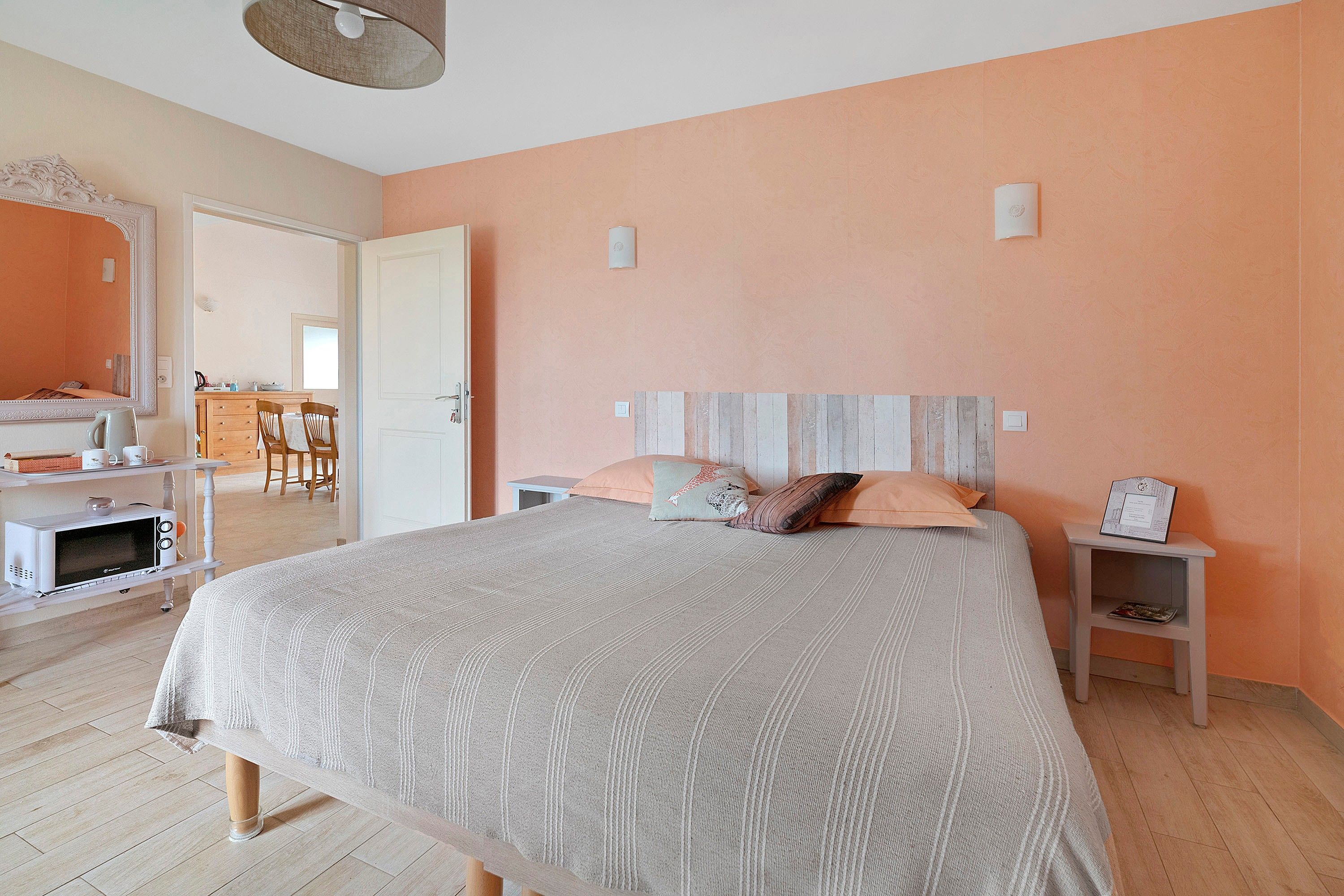 Un dormitorio con cama, mesitas de noche, cómoda, espejo y una puerta que da a un baño.