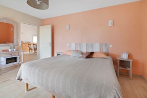A bedroom with a bed, bedside tables, a dresser, a mirror, and a door leading to a bathroom.