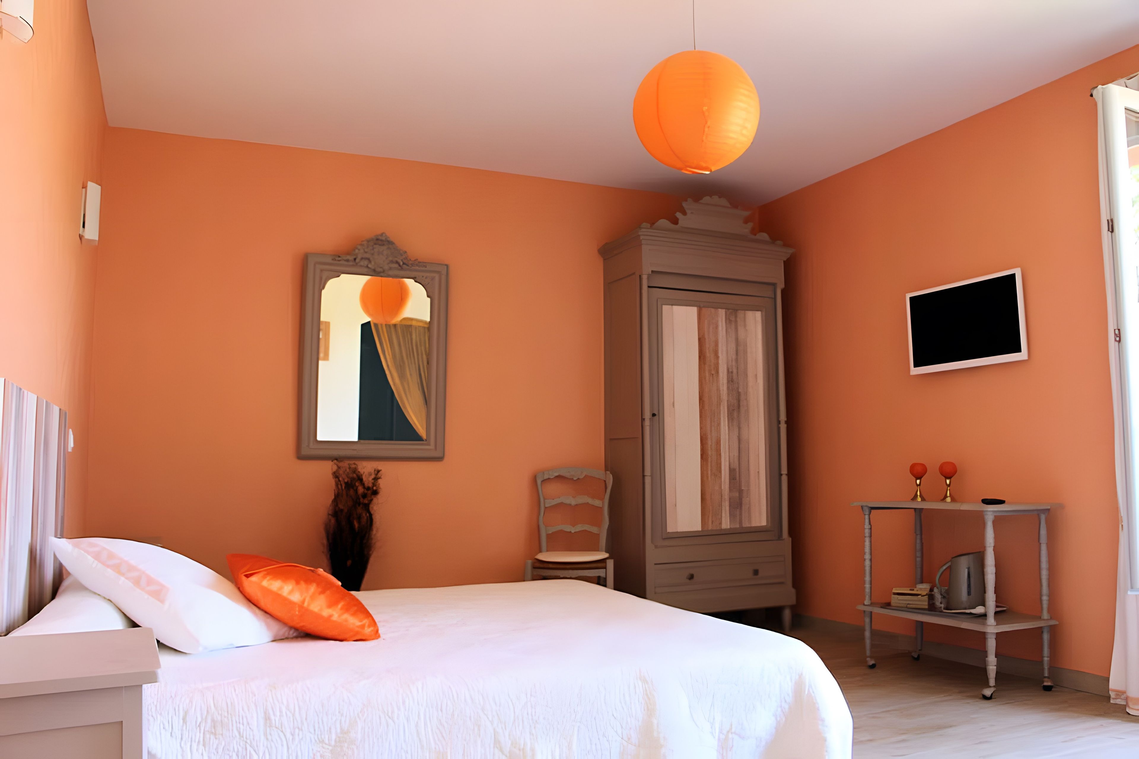 Een slaapkamer met een bed, een kledingkast, een spiegel en een televisie.