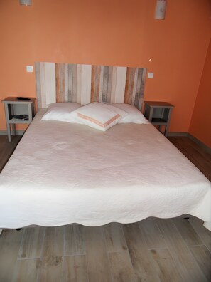 Ein Bett mit Holz-Kopfteil, zwei Nachttischen und einem hellen Boden.