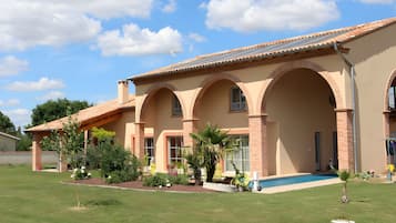 Un bâtiment à deux étages, doté d’un toit en tuiles, de fenêtres en arc de cercle et d’un patio couvert.