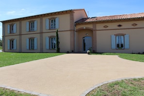 Un bâtiment à deux étages, doté d’une façade symétrique, d’une entrée centrale avec une porte et d’une allée pavée menant à l’entrée.