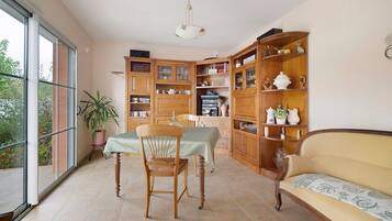 A dining area with a table and chairs, a wooden bookshelf, and a sofa.
