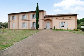 A two-story building with a gravel driveway leading to a front door.