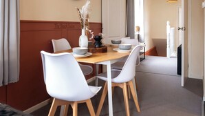 Un comedor con una mesa de madera, sillas blancas, un reloj de pared y un letrero que dice 'The Beach Suites'.