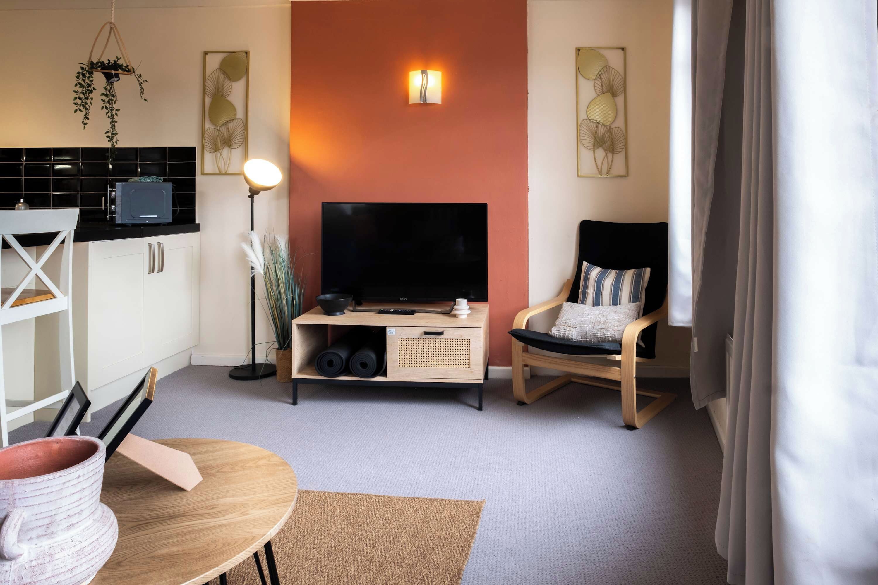 Un espace de vie compact comprenant un téléviseur à écran plat, une table à manger, une chaise et une petite kitchenette.
