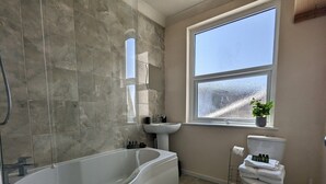 Un baño con bañera, lavabo, inodoro y ventana.