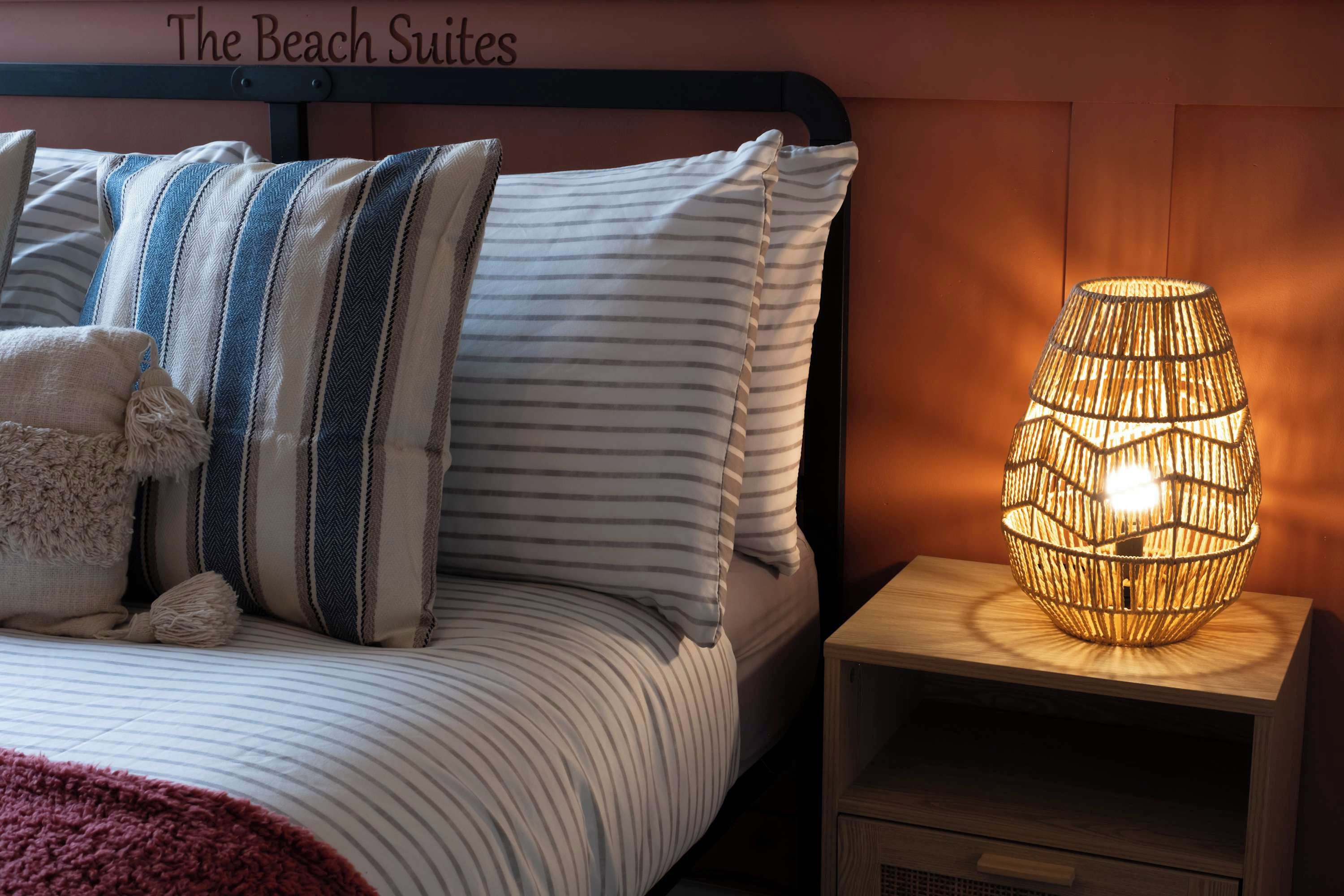 A neatly made bed with striped bedding and a decorative lamp on a bedside table.