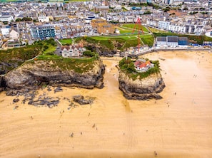 Vue aérienne d’une ville côtière avec ses bâtiments, sa plage et ses affleurements rocheux.