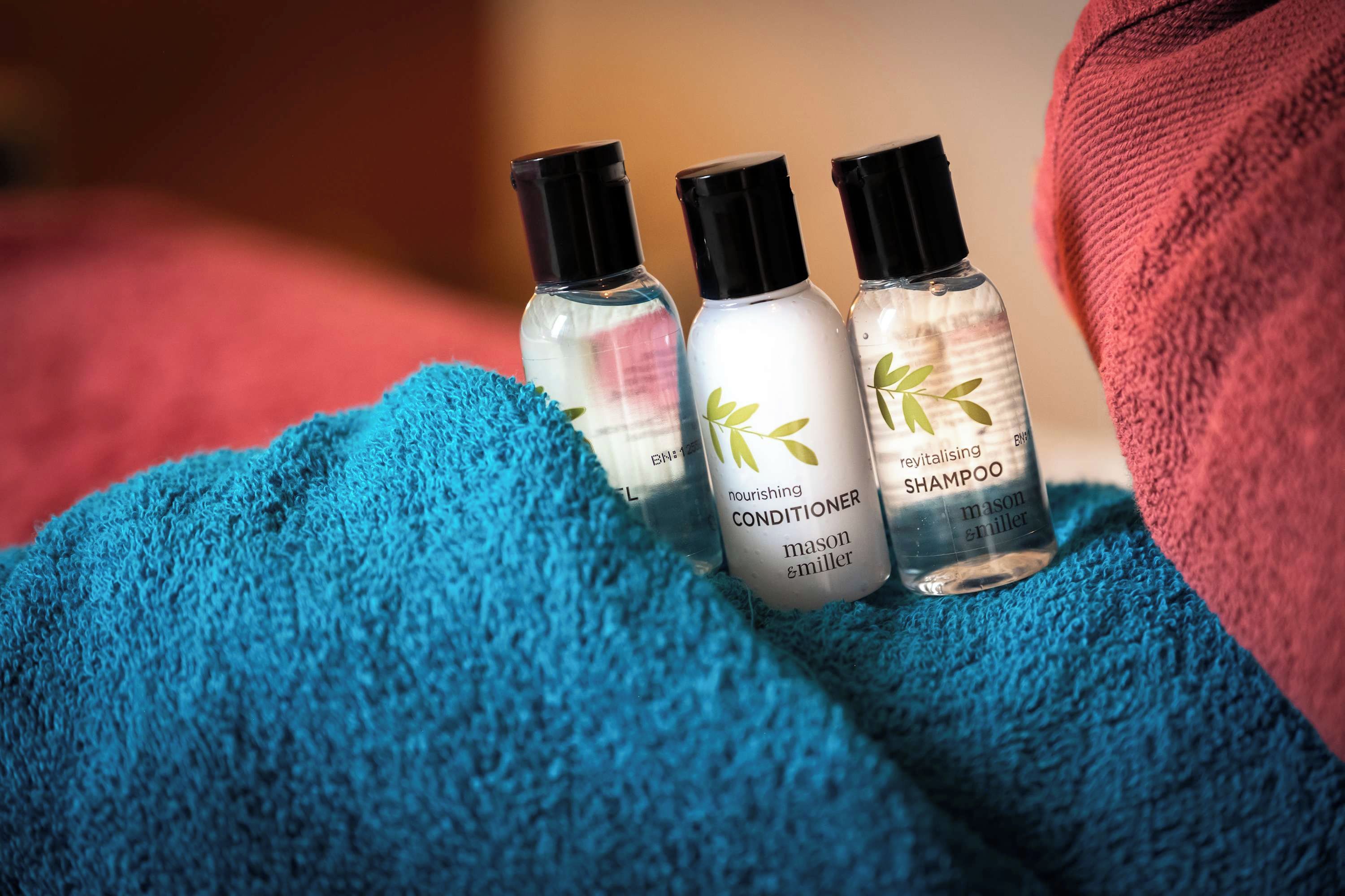 Three bottles of hair care products on a blue towel.