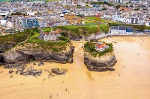 Une ville côtière dotée d’une plage de sable, de formations rocheuses et d’un bâtiment remarquable avec un toit rouge.