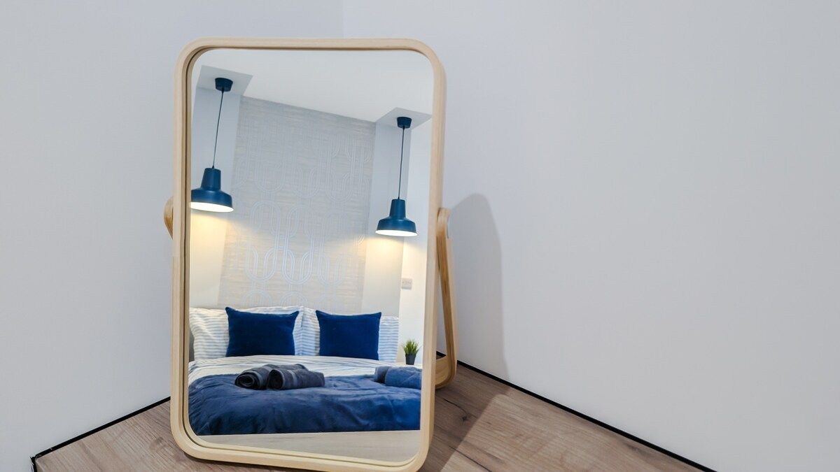Cama com roupa de cama azul, duas luminárias azuis e parede branca com textura.