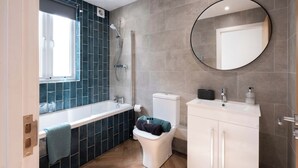Ein modernes Badezimmer mit Dusche, Toilette, Waschbecken und Spiegel.