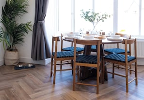Un coin repas avec une table ronde dressée pour quatre personnes, entourée de chaises en bois dotées d’assises rembourrées.