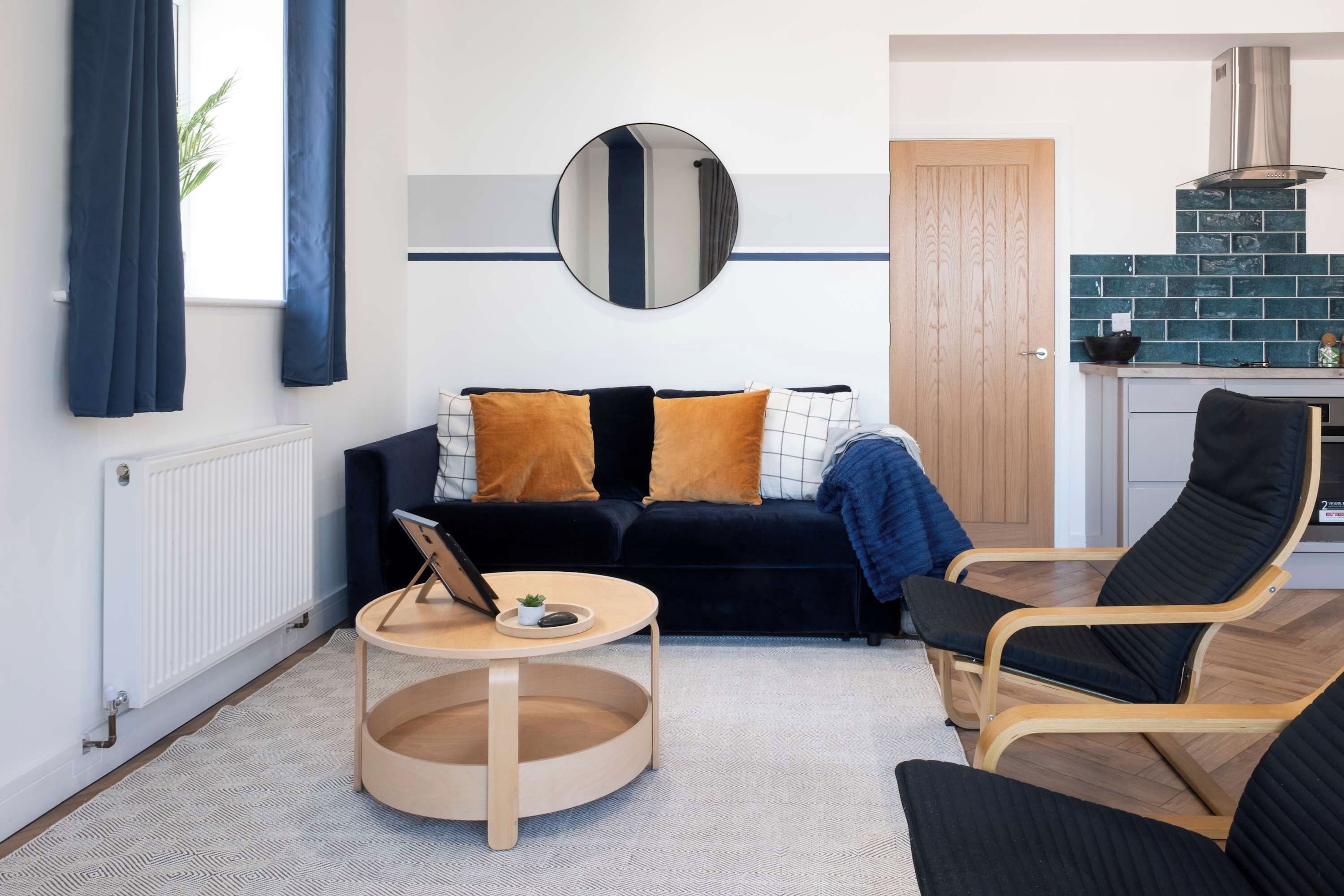 A modern living room with a dark sofa, a round coffee table, and a black armchair.