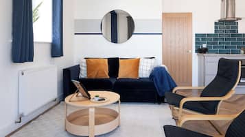 A modern living room with a dark sofa, a round coffee table, and a black armchair.